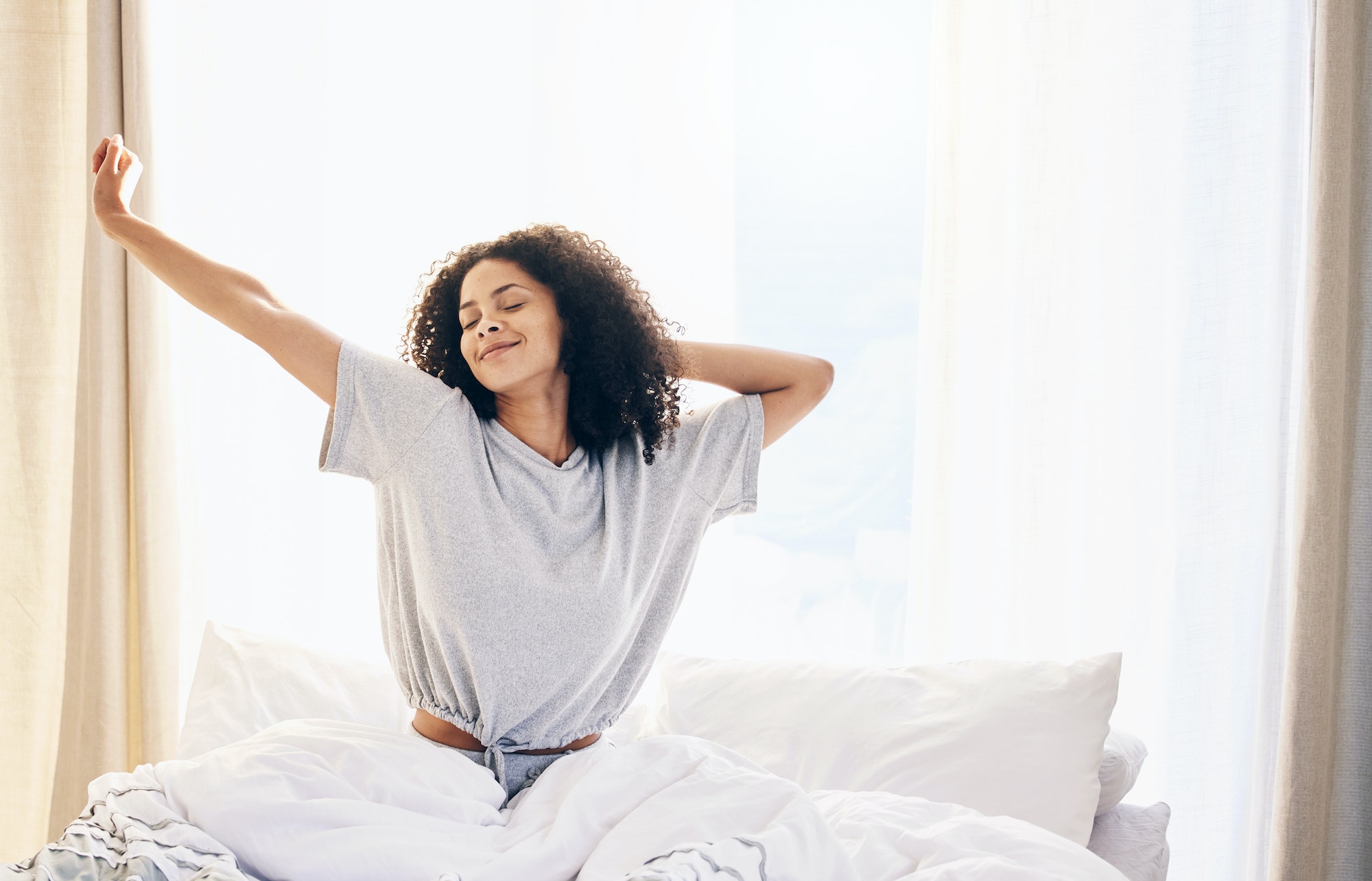Black woman, morning stretching and waking up in home bedroom after sleeping or resting. Relax, pea